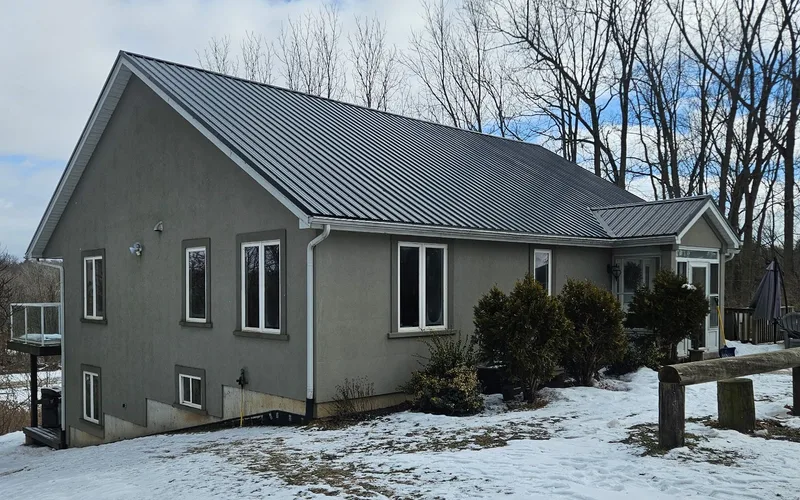 Grey house with a steel roof and white window trim